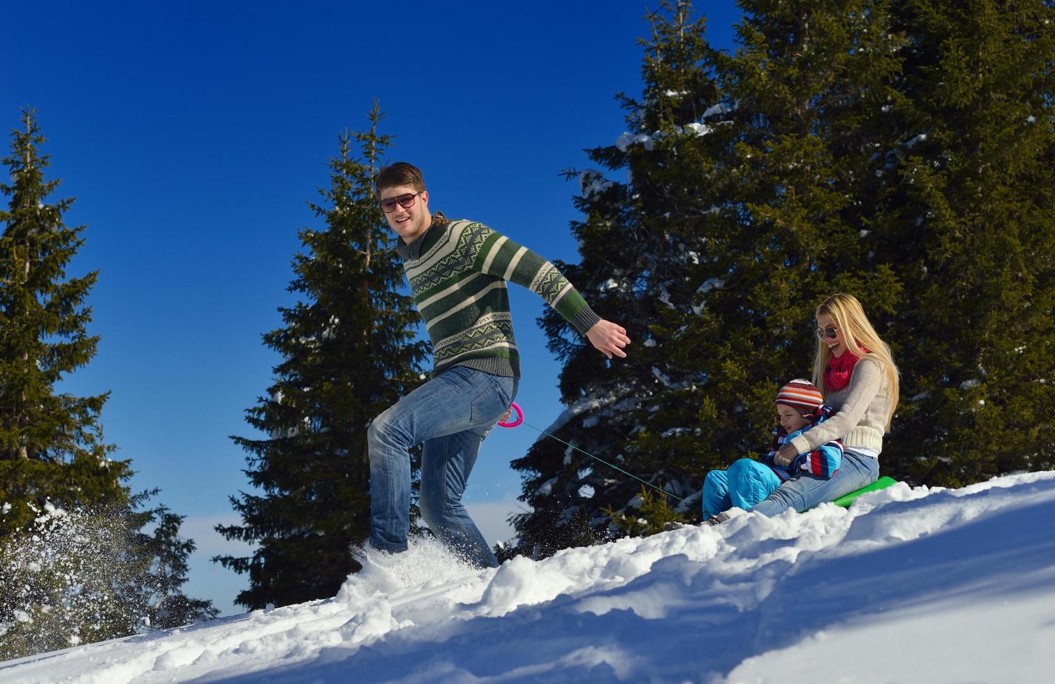 family having fun on fresh snow at winter vacation photo