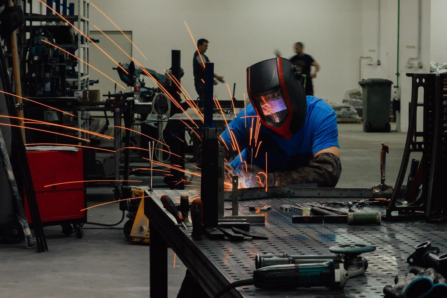 soldador profesional de la industria pesada que trabaja dentro de la fábrica, usa casco y comienza a soldar. enfoque selectivo foto