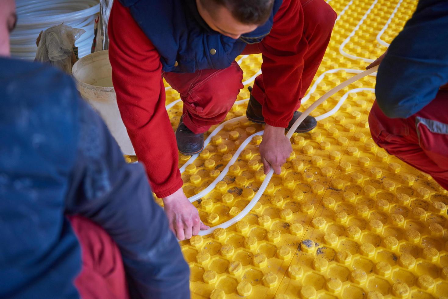 trabajadores instalando sistema de calefacción por suelo radiante foto