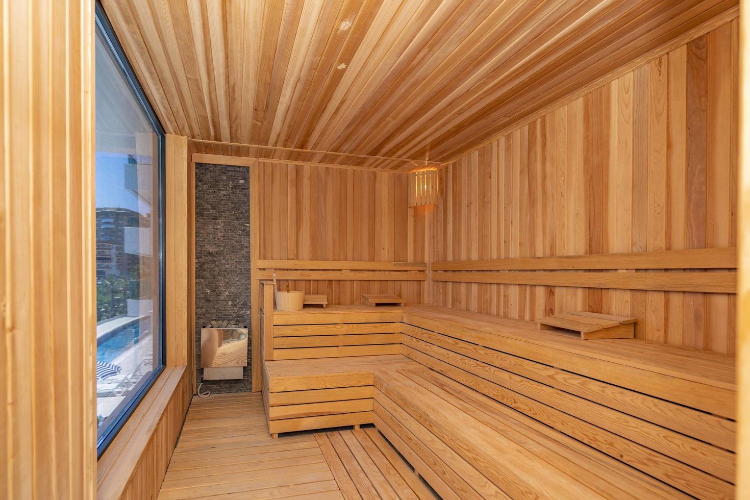 interior de sauna finlandesa, sauna clásica de madera con vapor caliente. baño ruso. relajarse en sauna caliente con vapor. baños interiores de madera, bancos de madera y tumbonas accesorios para sauna, spa complejo. foto