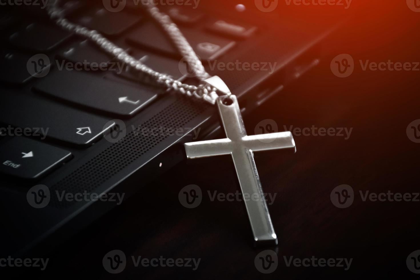 Metal cross necklace on notebook keyboard, soft and selective focus on cross necklace. photo