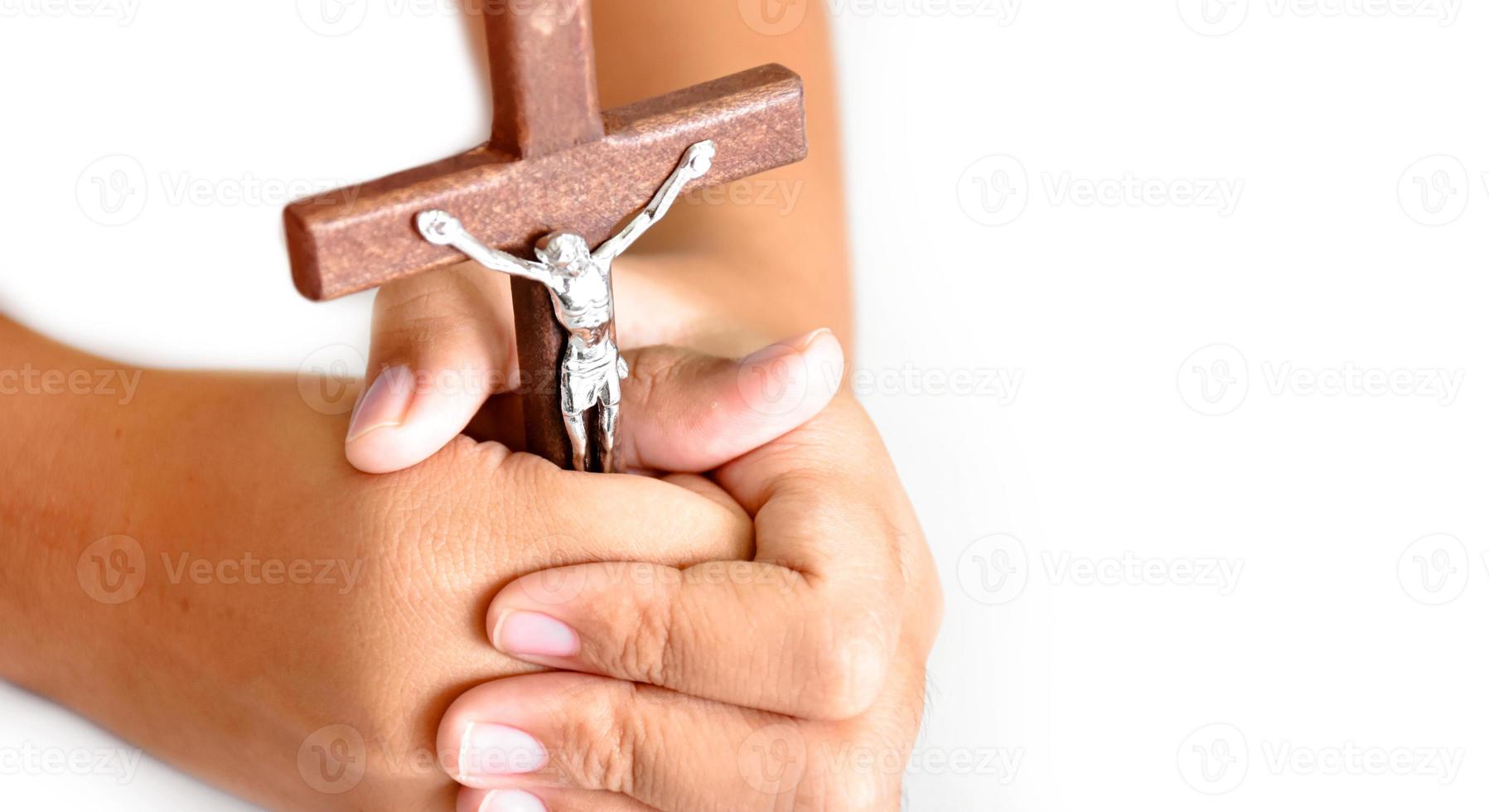 Wooden cross with a statue of Jesus crucified by his arm holding in hands of prayer on white table in the churce, soft and selective focus. photo