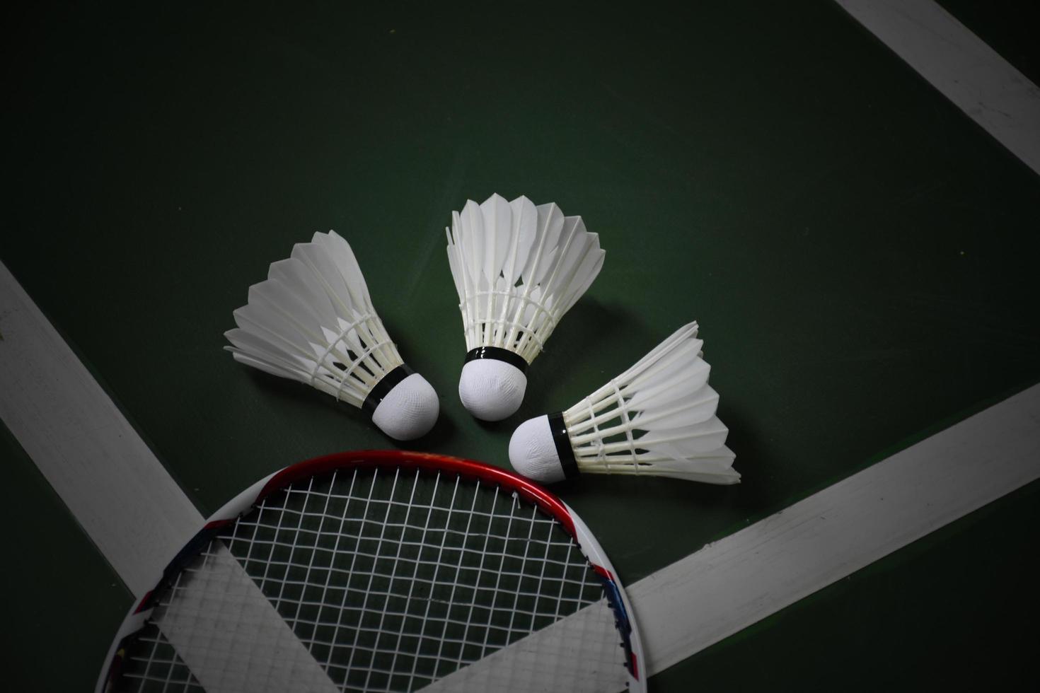 Cream white badminton shuttlecocks and rackets on green floor in indoor badminton court photo