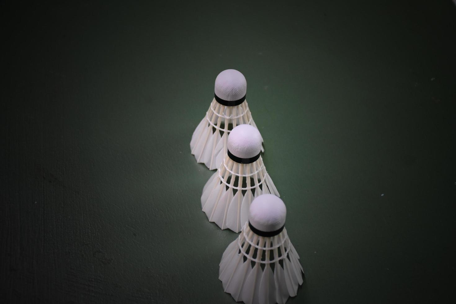 Cream white badminton shuttlecocks and rackets on green floor in indoor badminton court photo