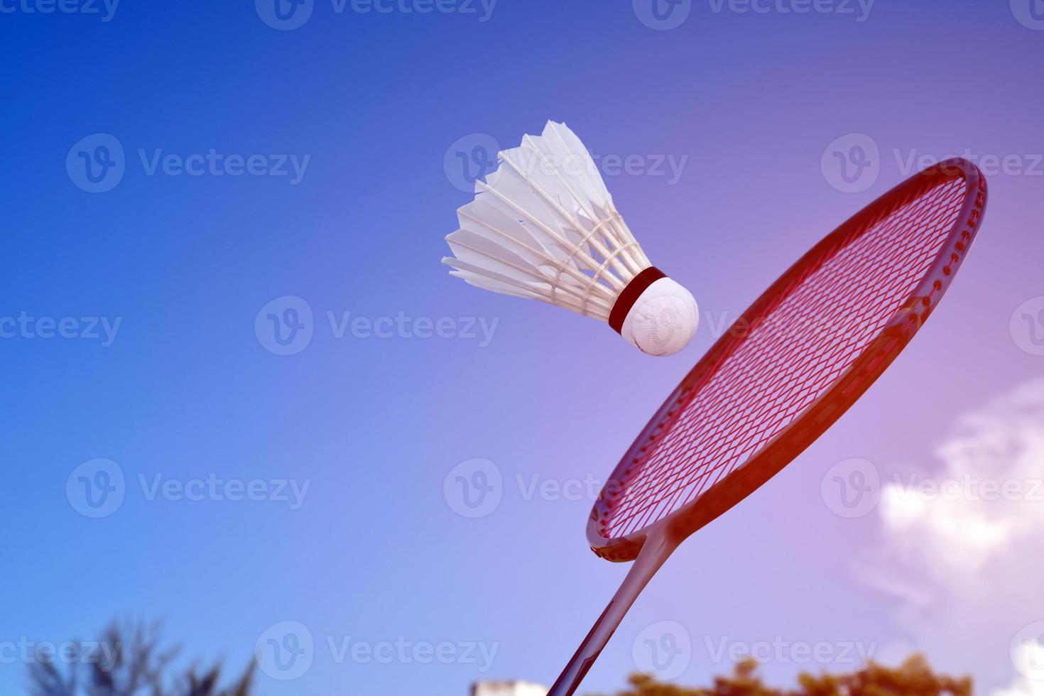 Badminton racket and badminton shuttlecock against cloudy and bluesky background, outdoor badminton playing concept. selective focus on racket. photo