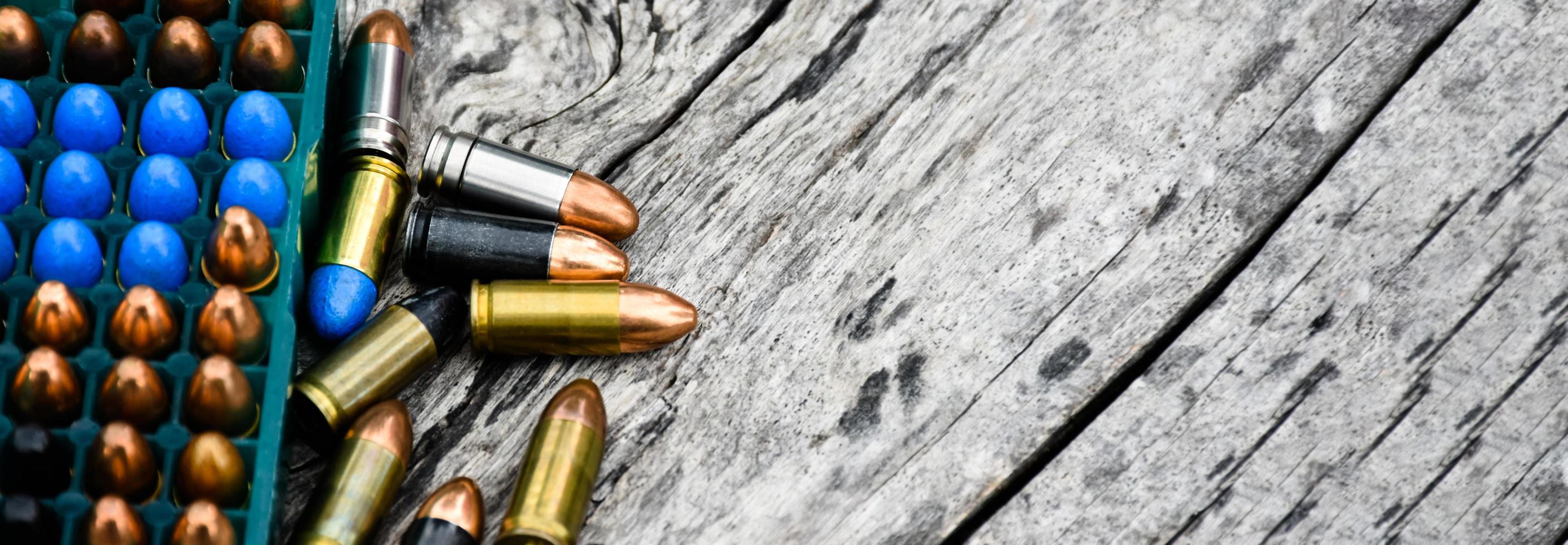 9mm pistol bullets and bullet shells on wooden table, soft and selectivec focus. photo