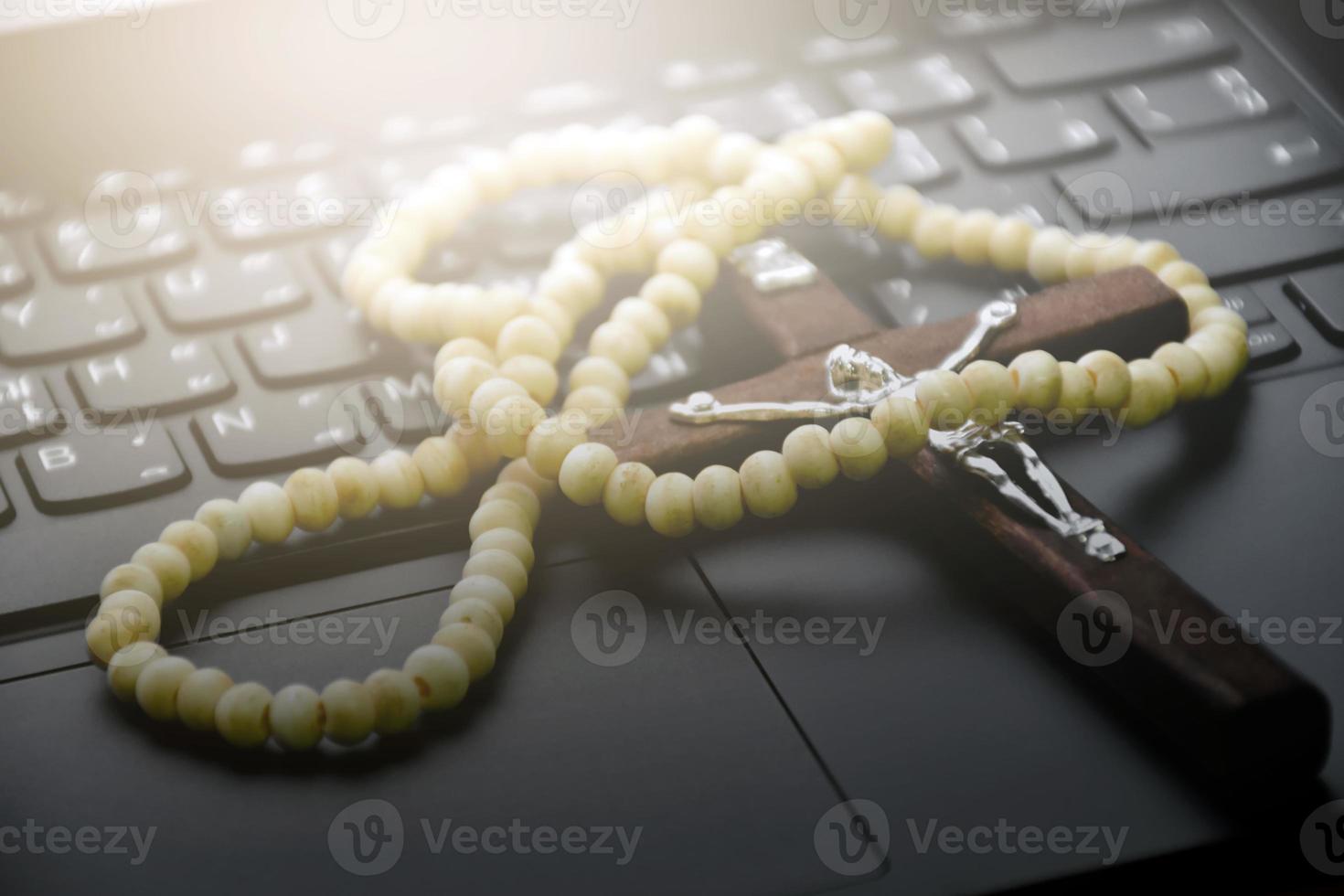 Metal cross necklace on notebook keyboard, soft and selective focus on cross necklace. photo