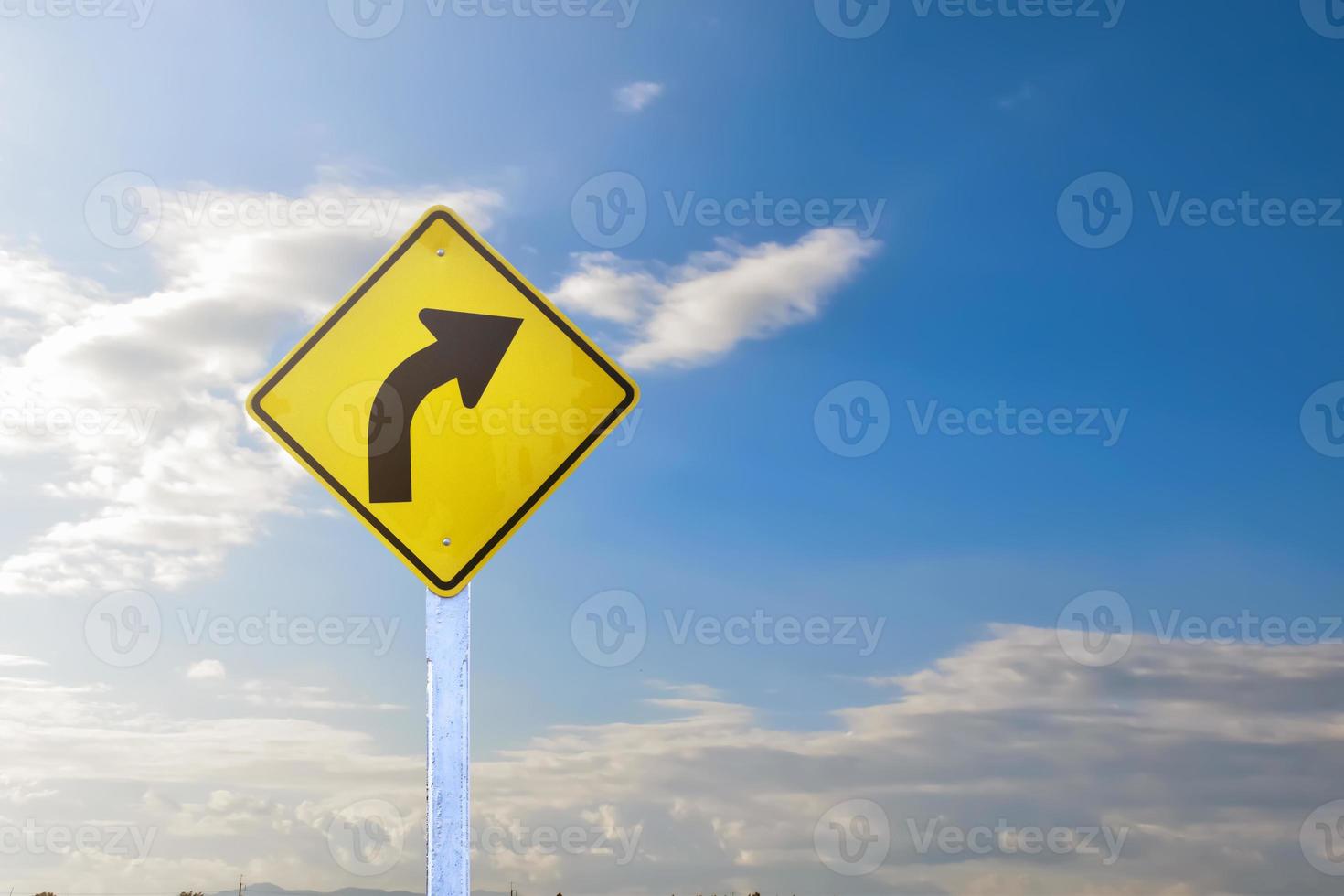 señal de tráfico señal de giro a la derecha en el poste de cemento al lado de la carretera rural con espacio de copia de fondo azul cielo nublado blanco foto