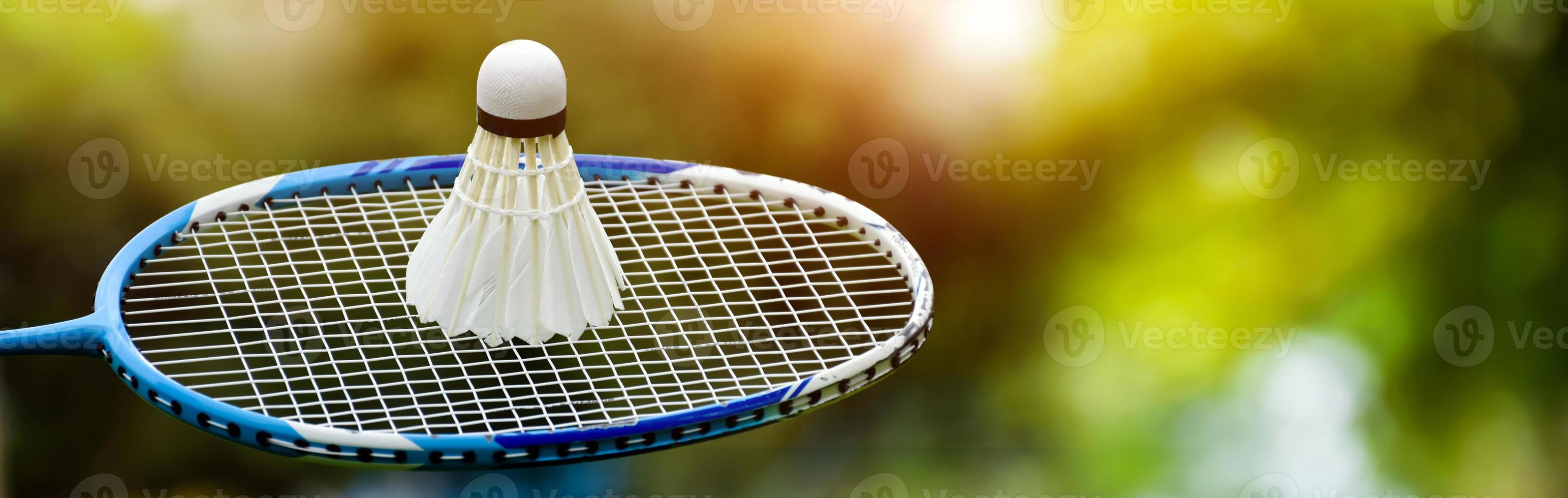 Badminton racket and badminton shuttlecock against cloudy and bluesky background, outdoor badminton playing concept. selective focus on racket. photo