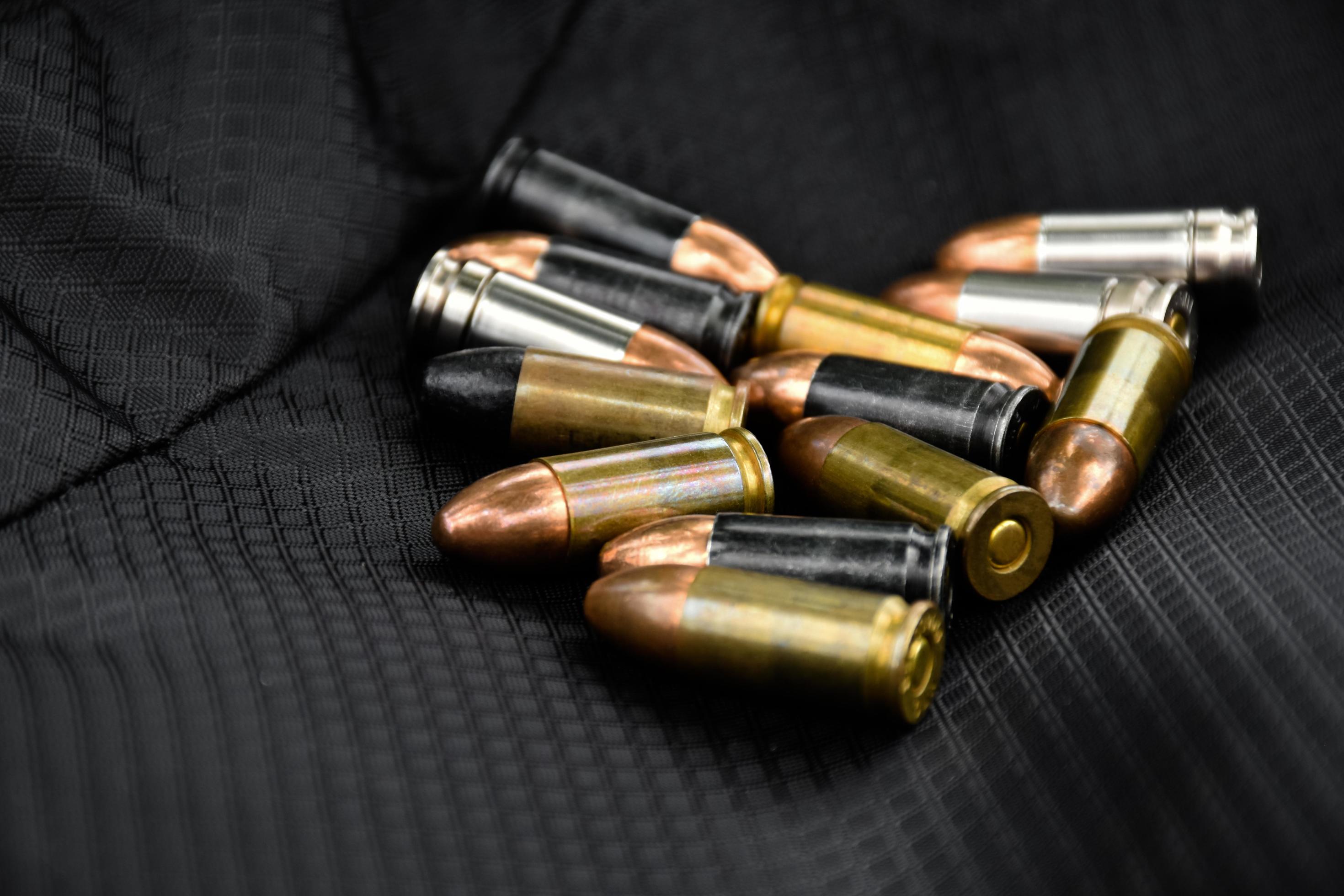 9mm pistol bullets and bullet shells on black leather background, soft