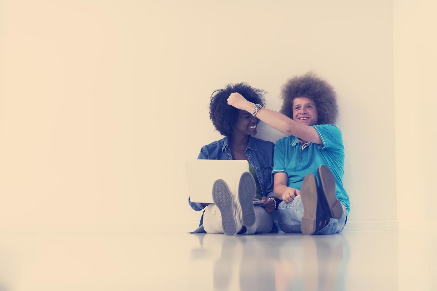 multiethnic couple sitting on the floor with a laptop and tablet photo