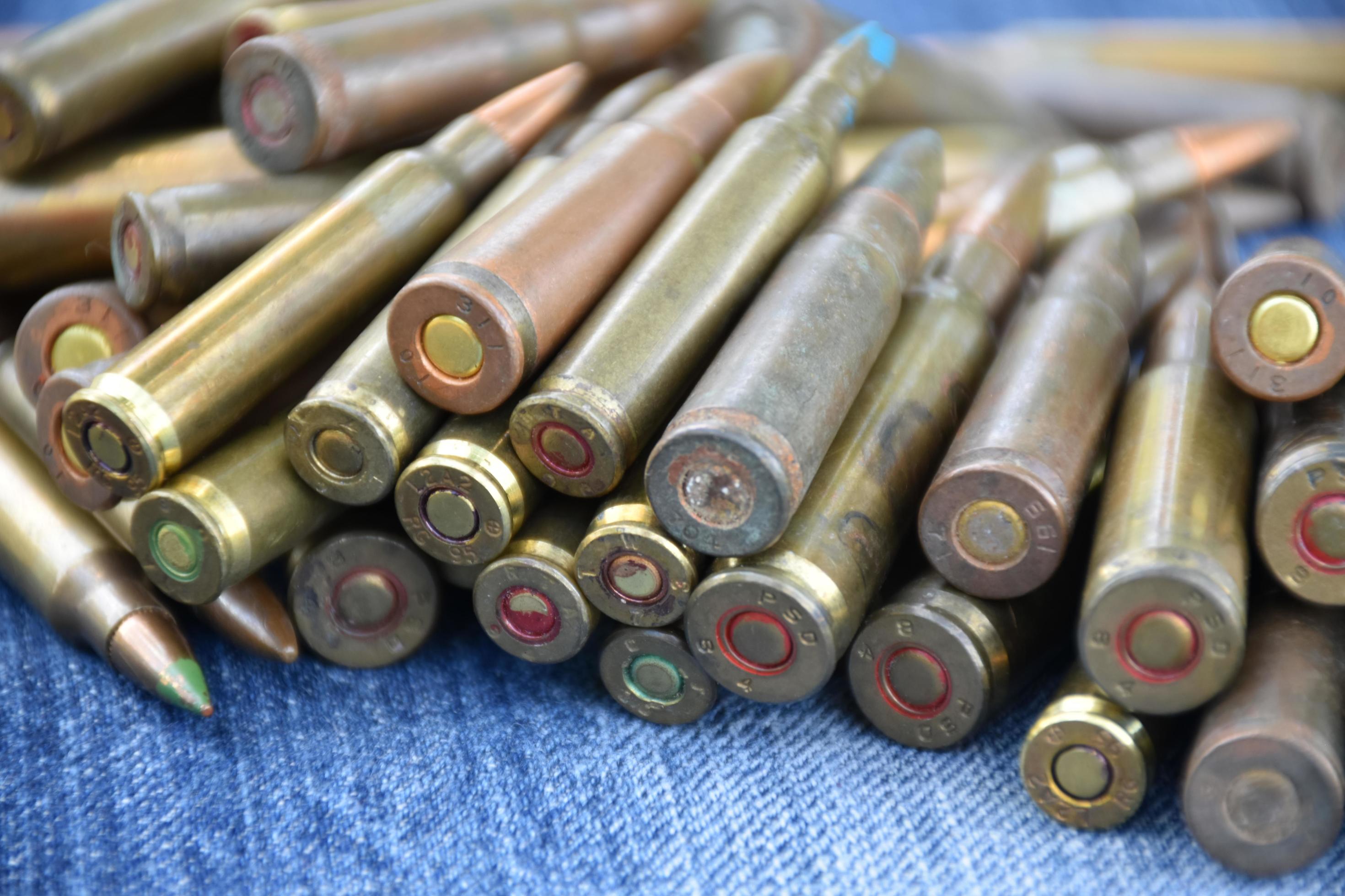 Pile of old bullets on wooden plank and jeans, soft and selective focus