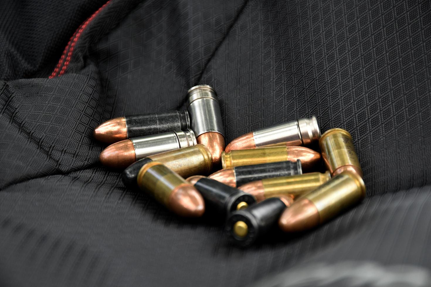 9mm pistol bullets and bullet shells on black leather background, soft and selectivec focus. photo