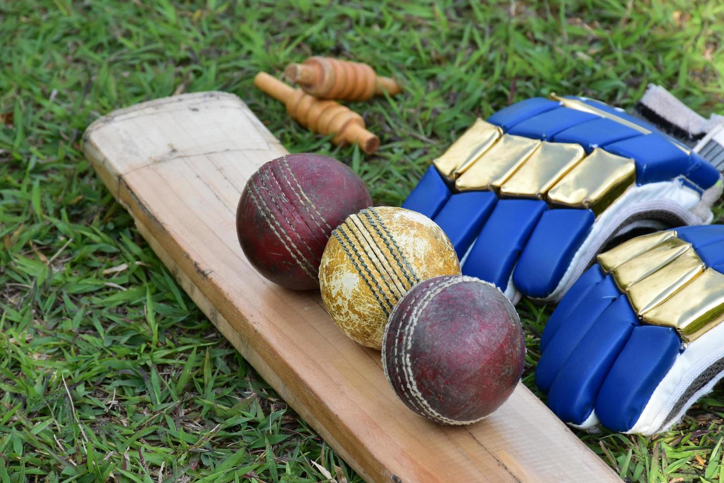 Cricket sport equipments bat ball gloves on green lawn  blurred green grass cricket field, concept for using cricket sport equipment in training. photo