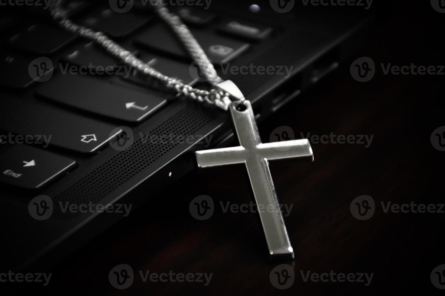 Metal cross necklace on notebook keyboard, soft and selective focus on cross necklace. photo