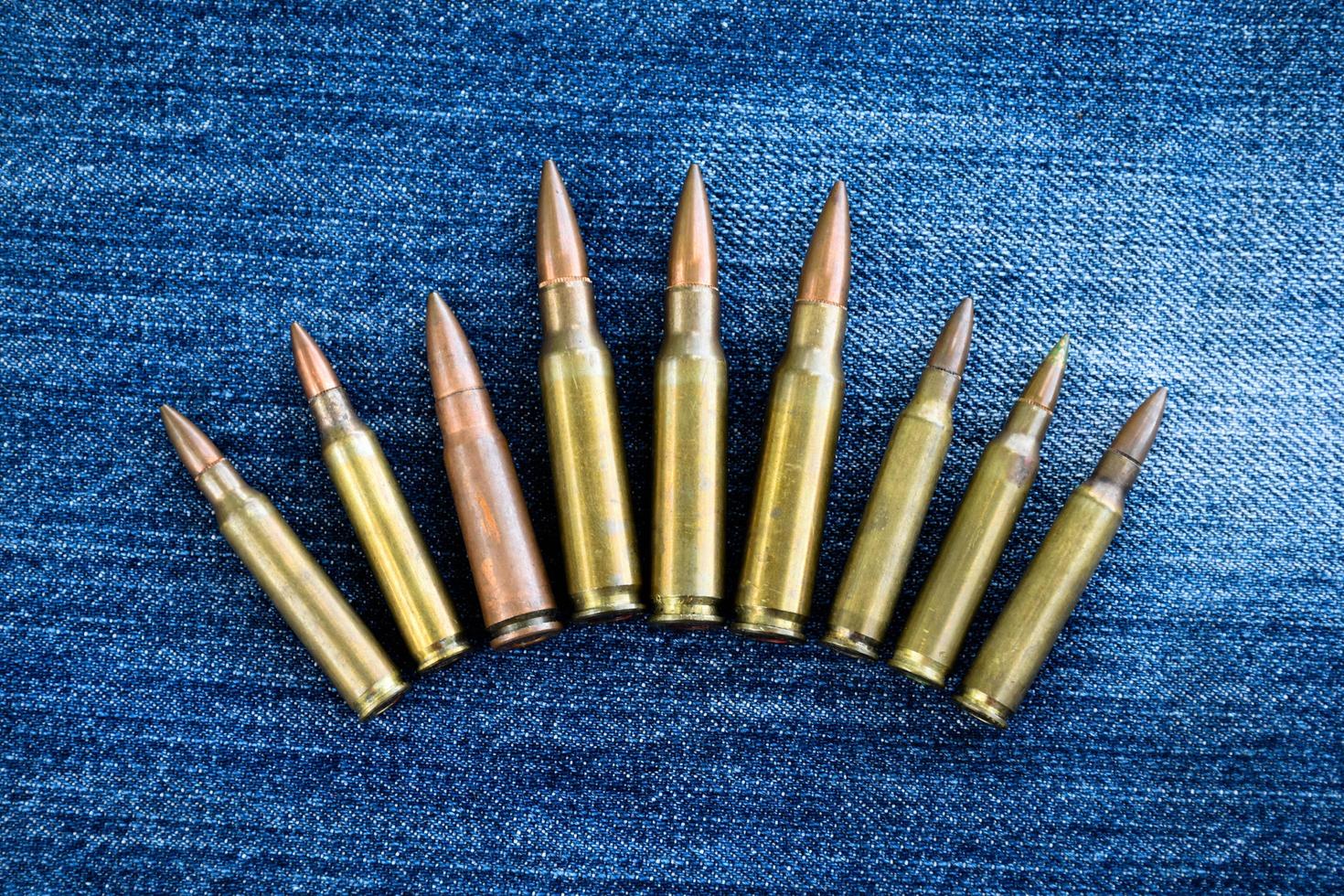 Pile of old bullets on wooden plank and jeans, soft and selective focus. photo