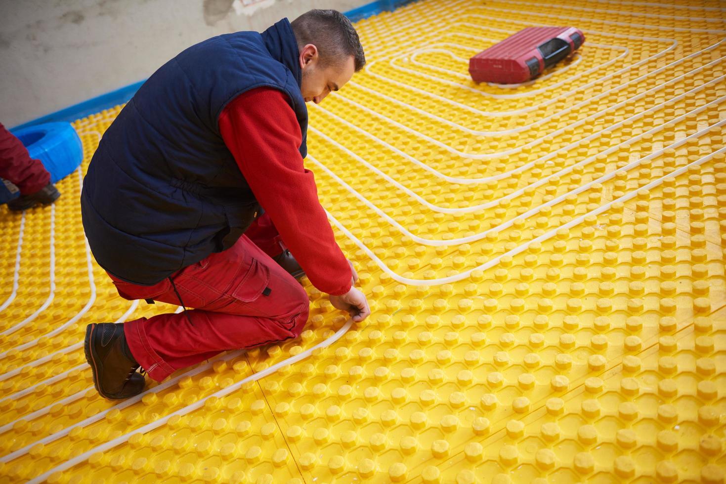 trabajadores instalando sistema de calefacción por suelo radiante foto