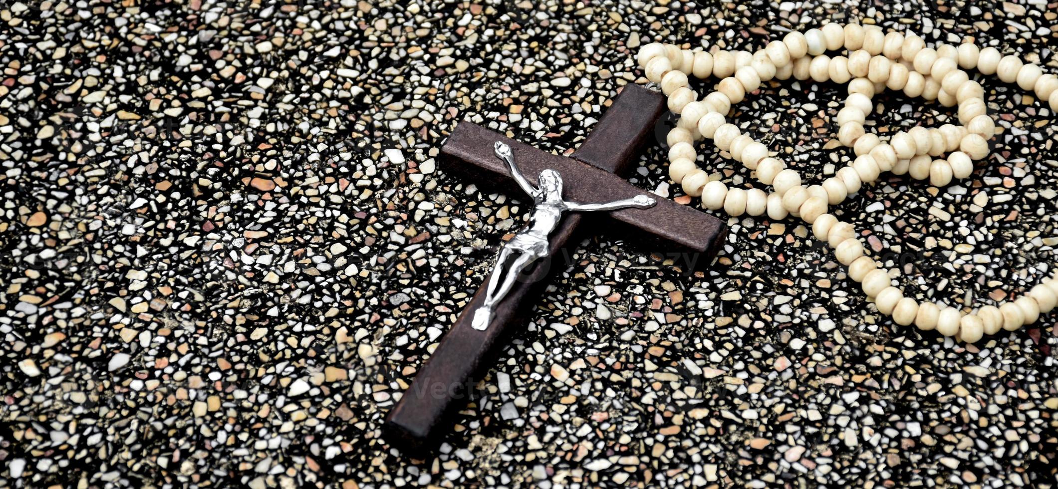 Wooden cross bead necklace hanging, natural blurr bokeh trees background, soft and selective focus. photo