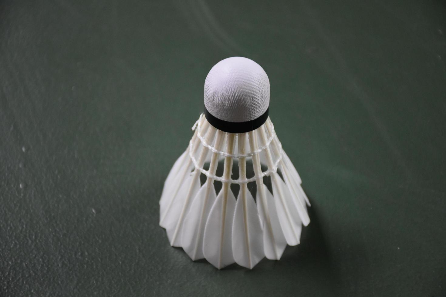 Cream white badminton shuttlecocks and rackets on green floor in indoor badminton court photo
