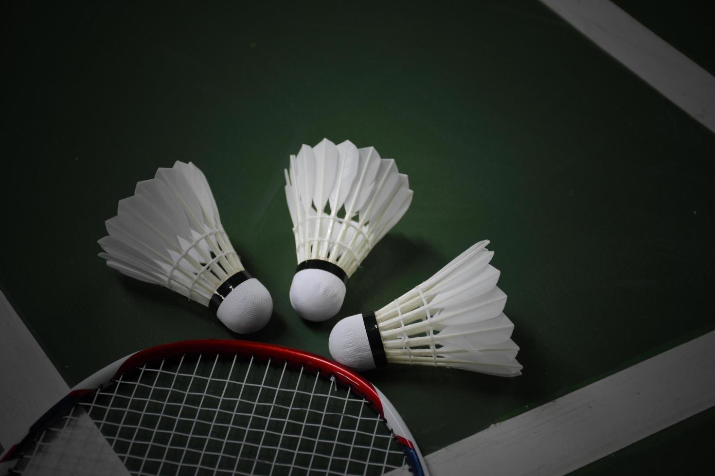 volantes y raquetas de bádminton blanco crema en el suelo verde en la cancha de bádminton cubierta foto