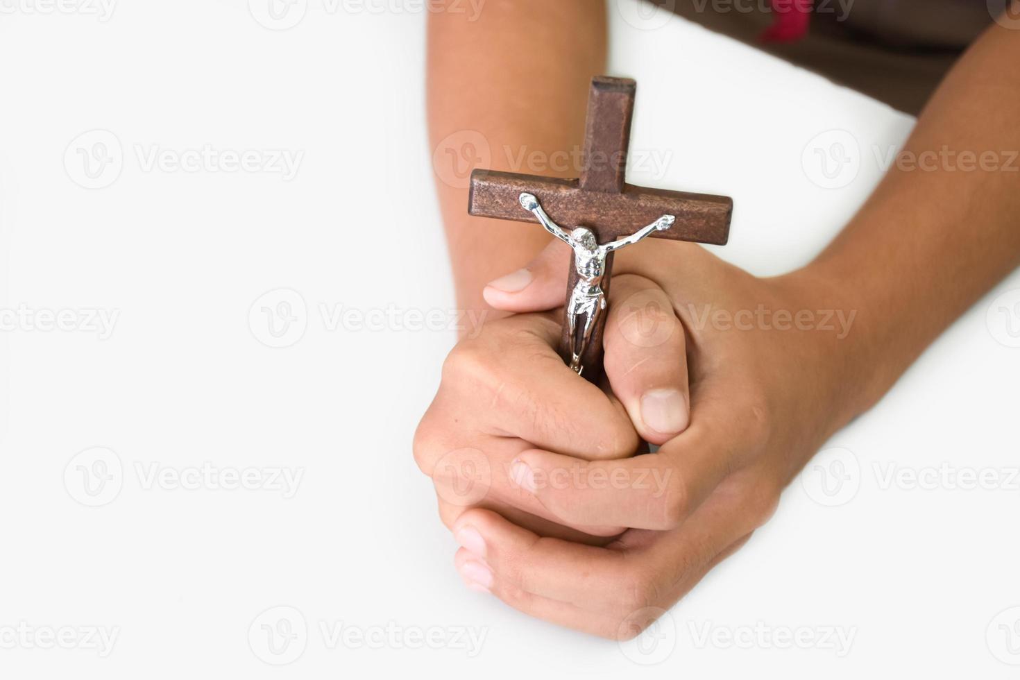 Wooden cross with a statue of Jesus crucified by his arm holding in hands of prayer on white table in the churce, soft and selective focus. photo