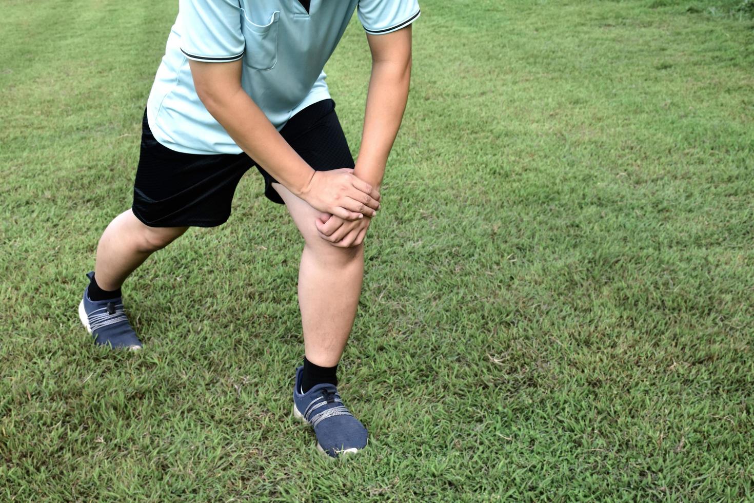 Middle aged asian man runner stretching on the grass lawn relaxing after and before running in the park. Healthy lifestyle with outdoor exercising concept photo