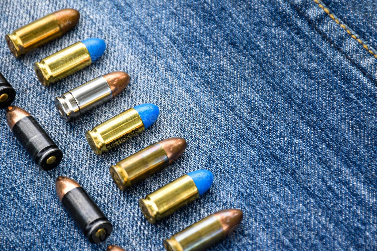 9mm pistol bullets and bullet shells on blue jeans, soft and selectivec focus. photo