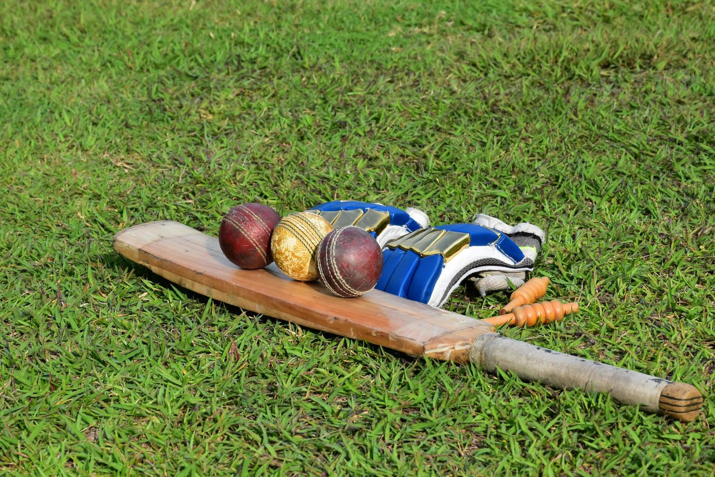 equipos deportivos de cricket guantes de pelota de bate en césped verde campo de cricket de hierba verde borrosa, concepto para usar equipos deportivos de cricket en el entrenamiento. foto