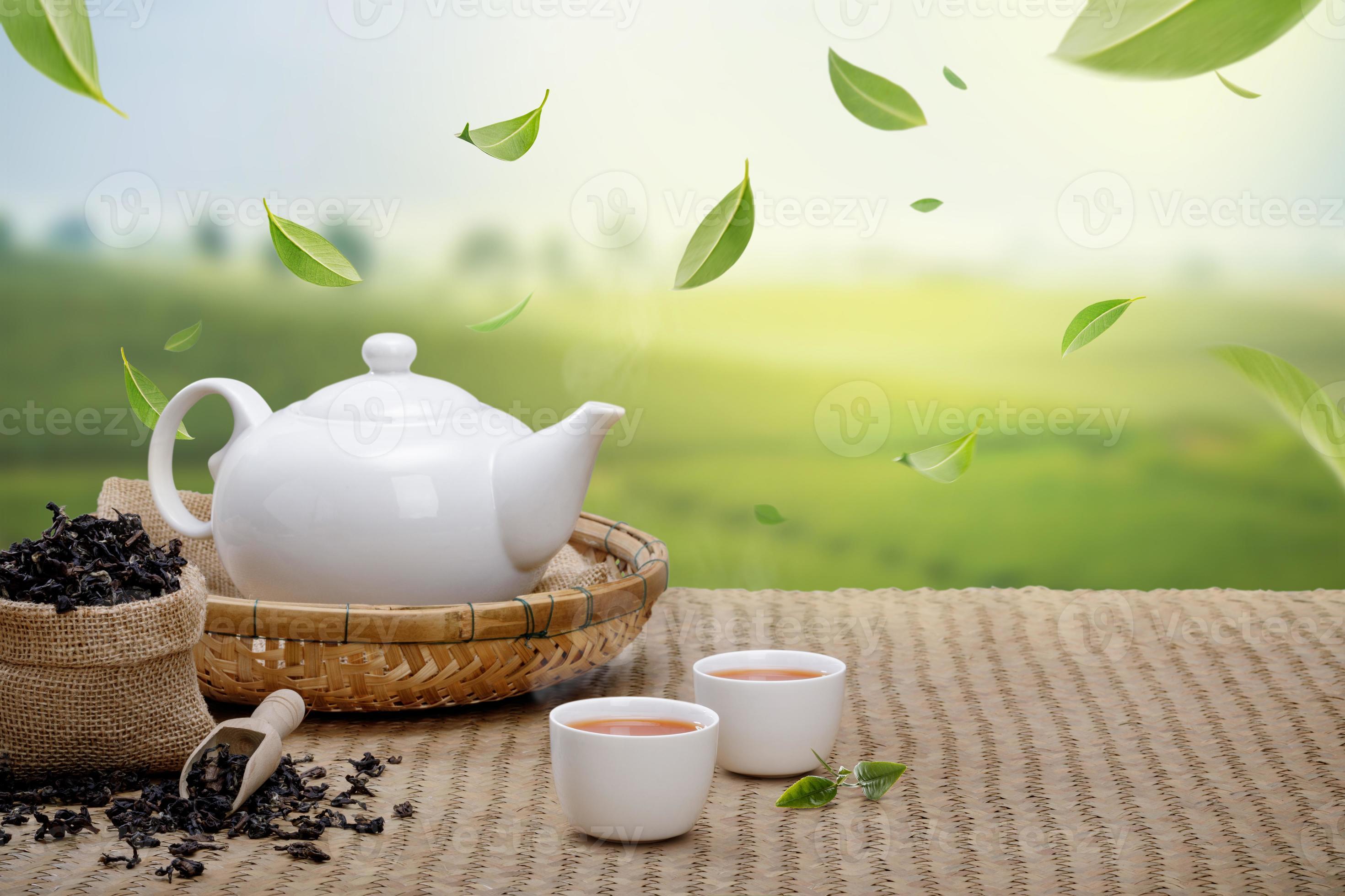 Warm cup of tea with teapot, flying green tea leaves in the air and