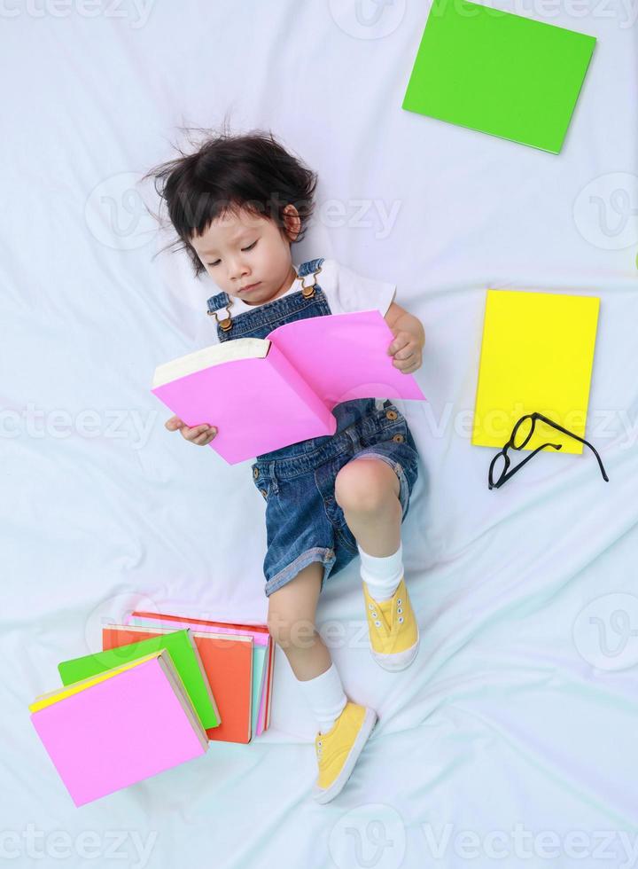 Child little asian girl or a little cute asian girl reading a book in the bed photo