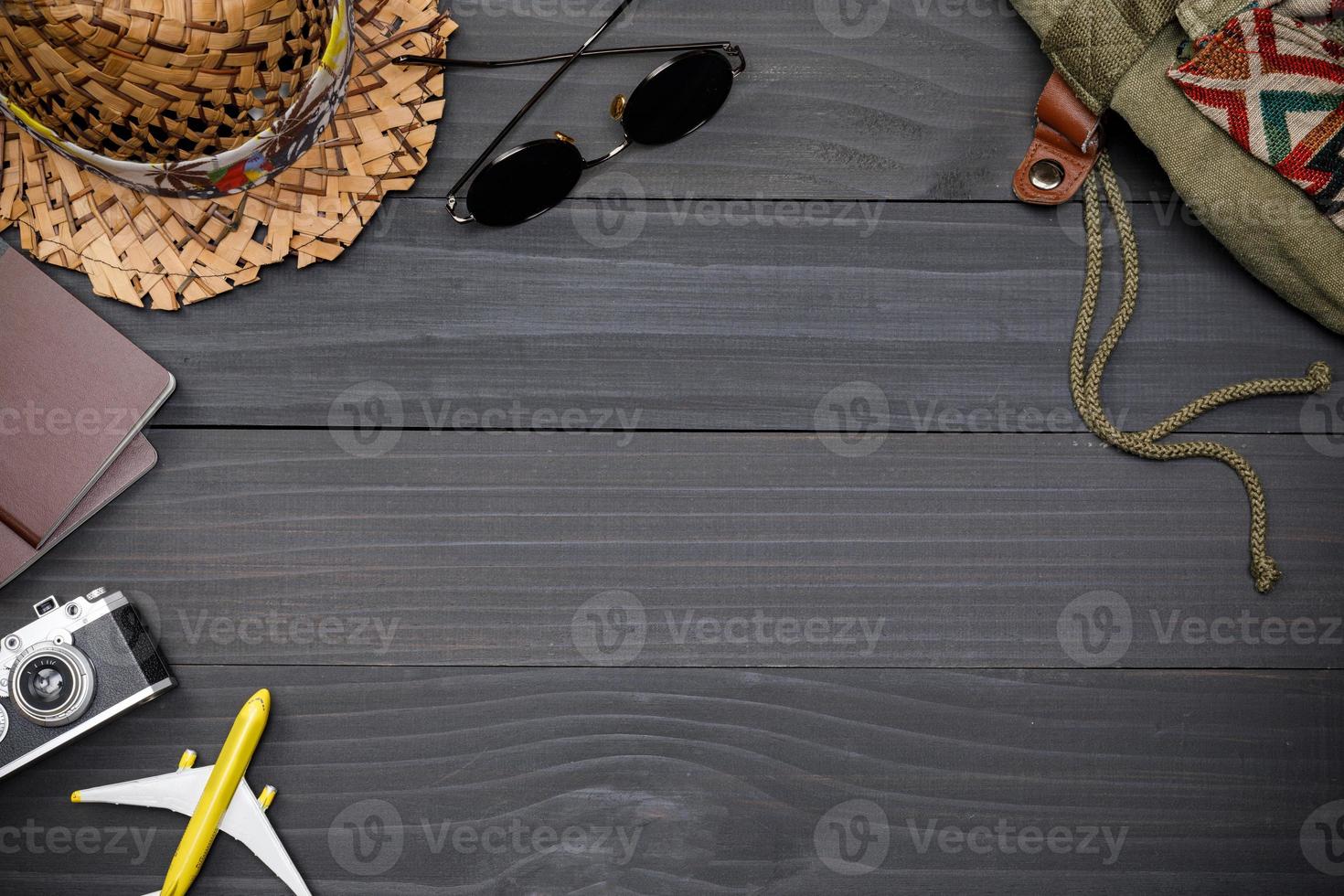 Traveler's accessories with passport, books of travel plan, wallet, camera, hat, backpack and airplane toy on black wooden table, Flat lay with copy space, Travel concept background photo