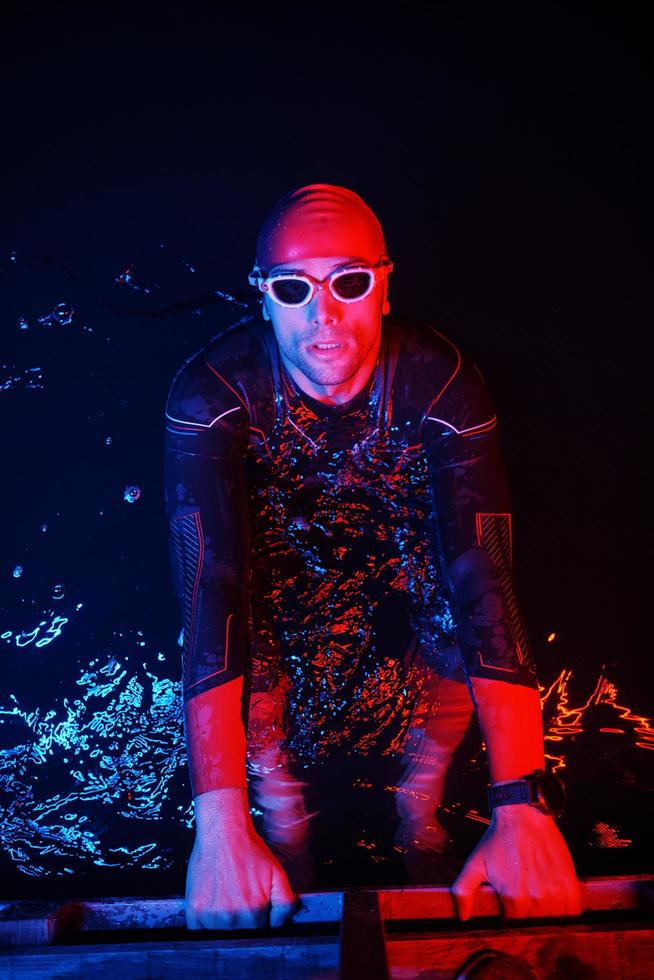 authentic triathlete swimmer having a break during hard training on night neon gel light photo