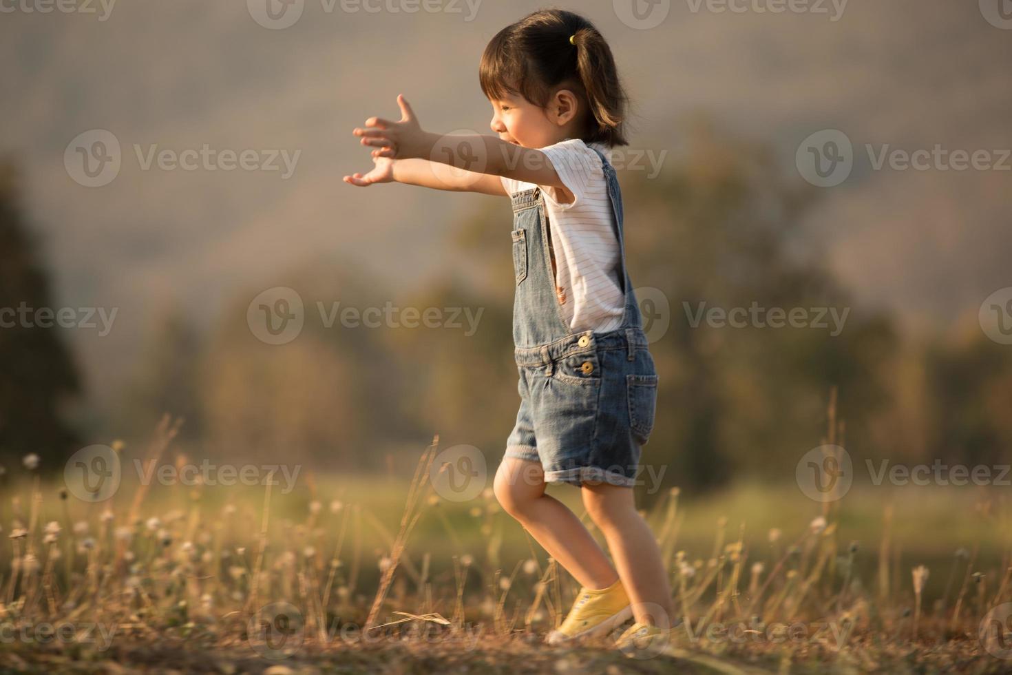 niña corriendo sobre la hierba verde. hermosa tarde cálida de verano. foto