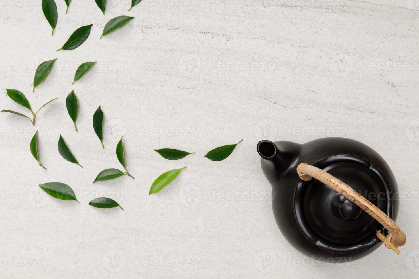 Teapot with organic green tea leaves on the white stone desk empty space creative flat lay, Organic product from the nature for healthy with traditional style photo