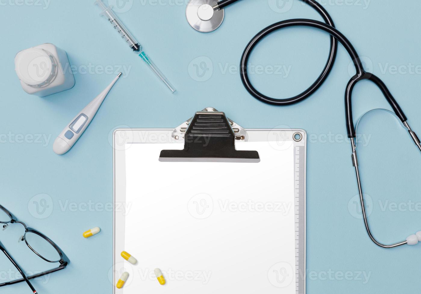 Doctor medical equipment blue table with stethoscope, medical documents, thermometer, syringe and pills with copy space mockup template photo