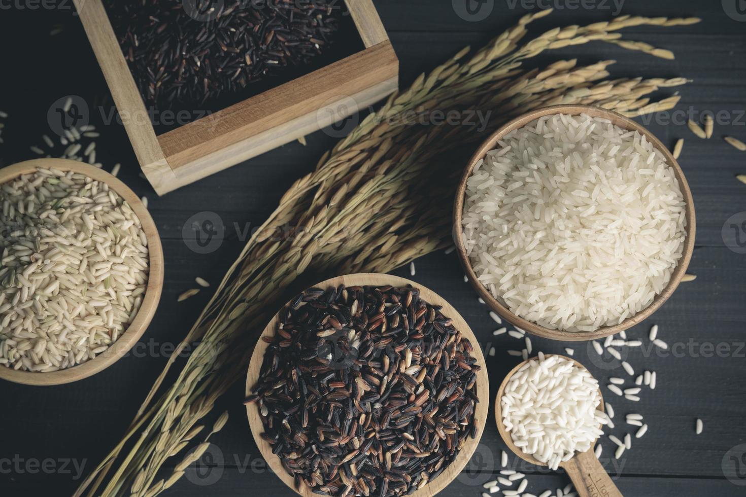 arroz japonés con arroz jazmín tailandés y semillas de arroz con cáscara en una mesa de madera foto