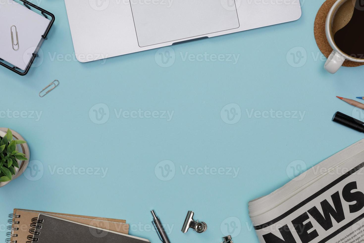 maqueta de suministros de oficina del espacio de trabajo de vista superior con cuaderno, taza de café caliente, vasos, periódico y accesorios aislados en fondo azul, vista superior con espacio de copia, espacio de trabajo para el concepto de diseñador foto