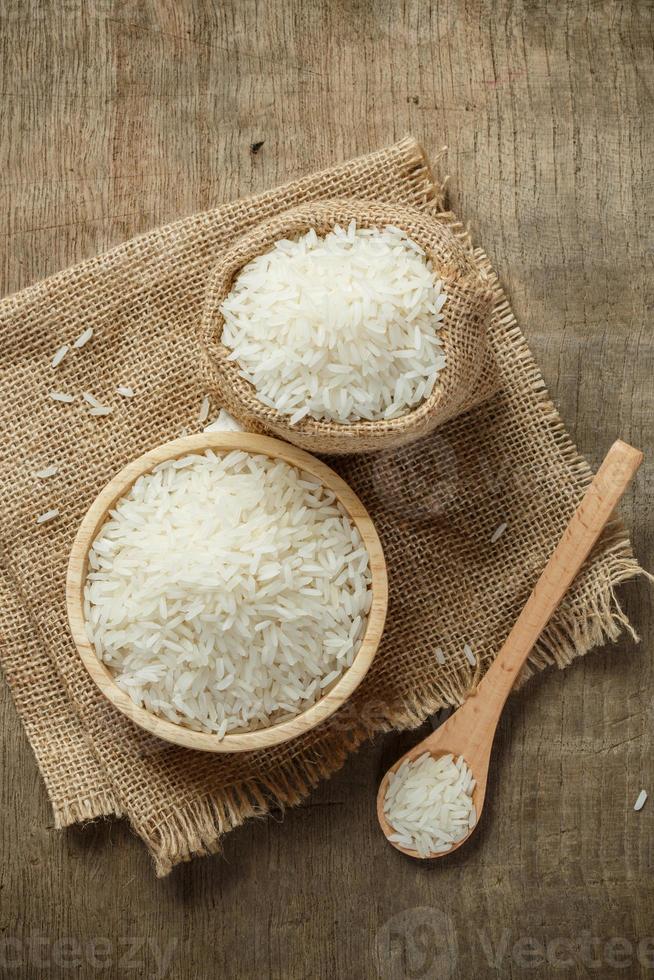 arroz jazmín en tazón y saco en mesa de madera foto