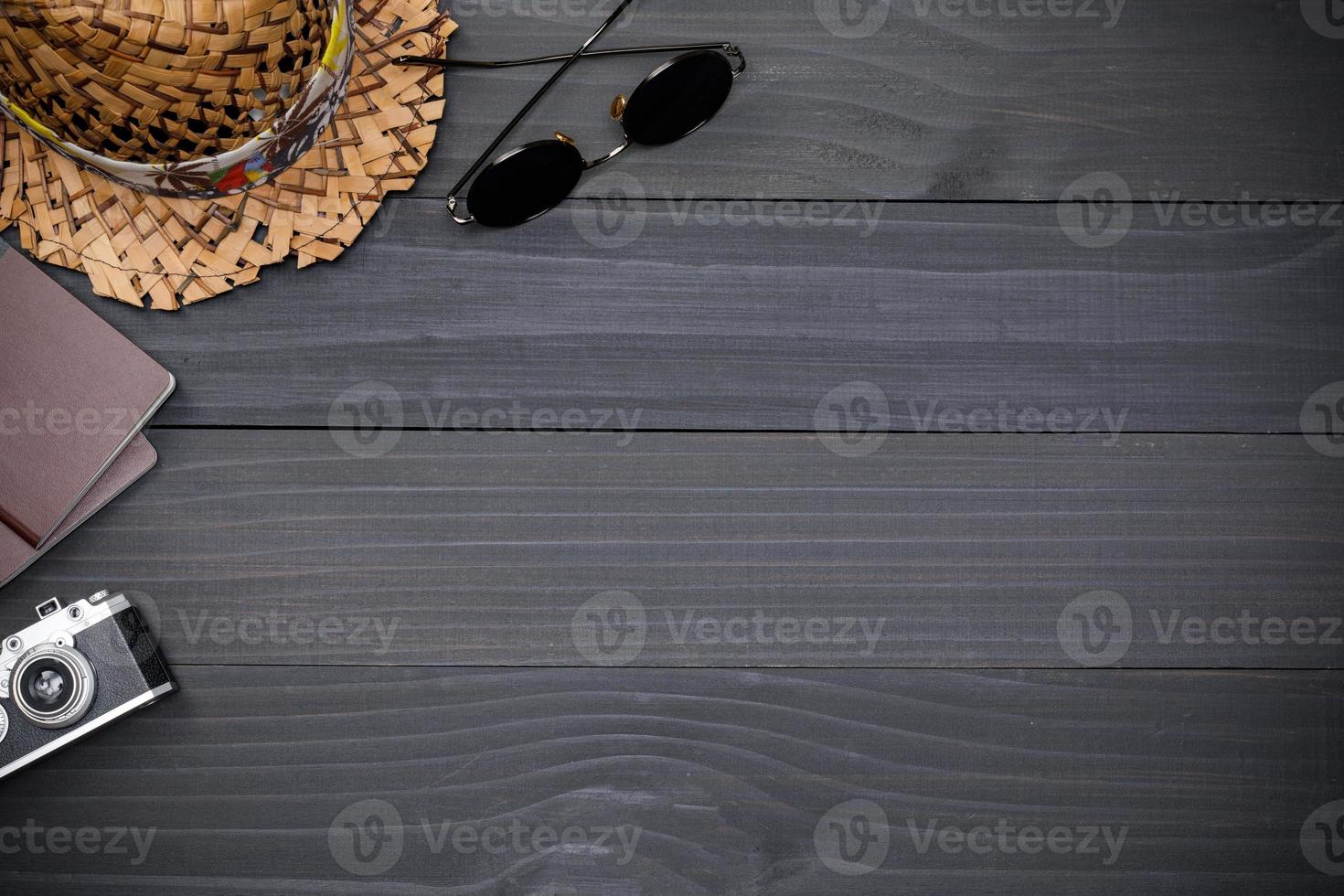 Top view mockup of Traveler's accessories with passport, wallet, camera and hat on black wooden desk empty space, Travel concept background photo