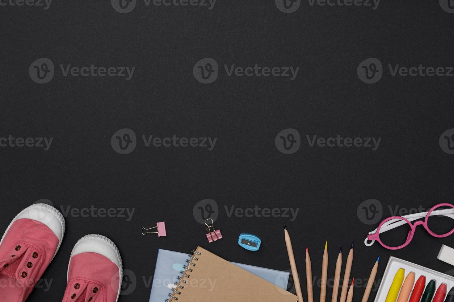 Creative flatlay of education green table with student books, shoes, colorful crayon, eye glasses, empty space on blackboard background, Concept of education and back to school photo