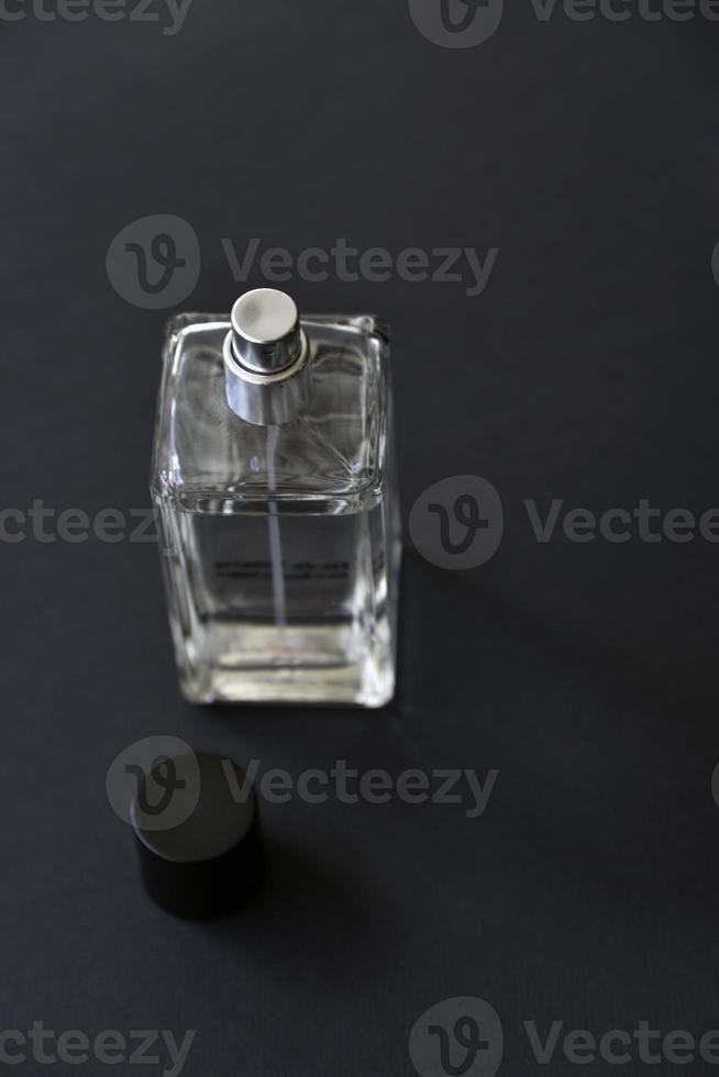 una botella de vidrio con perfume sobre un fondo negro. una hermosa botella con un dispensador de spray de perfume. foto
