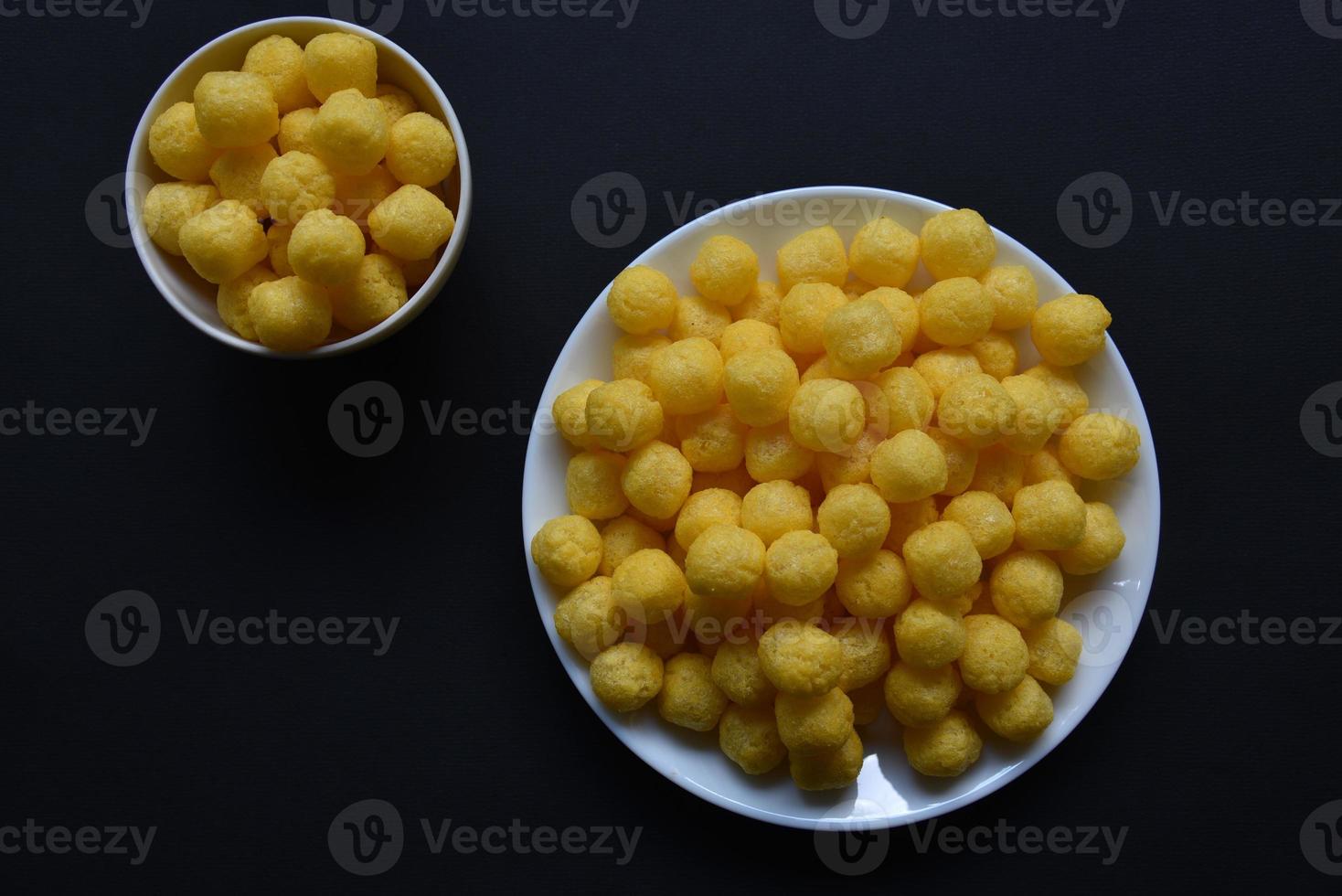 Corn salted and peppered chips on a white plate. Delicious breakfast of corn chips on a black background. photo