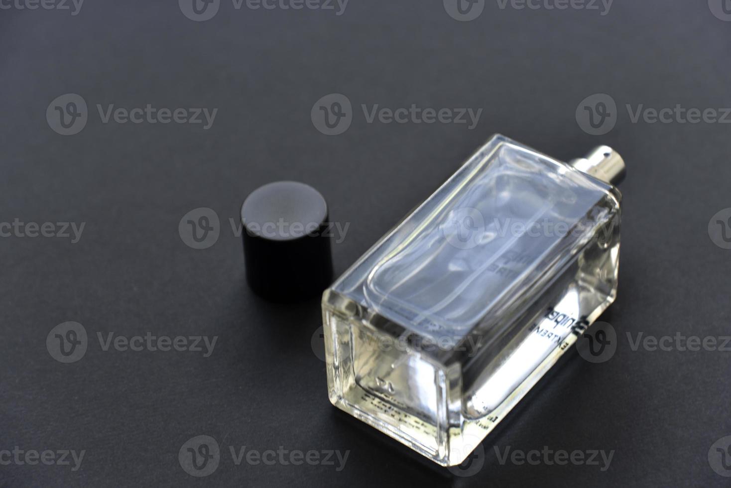A glass bottle with perfume on a black background. A beautiful bottle with a perfume spray dispenser. photo