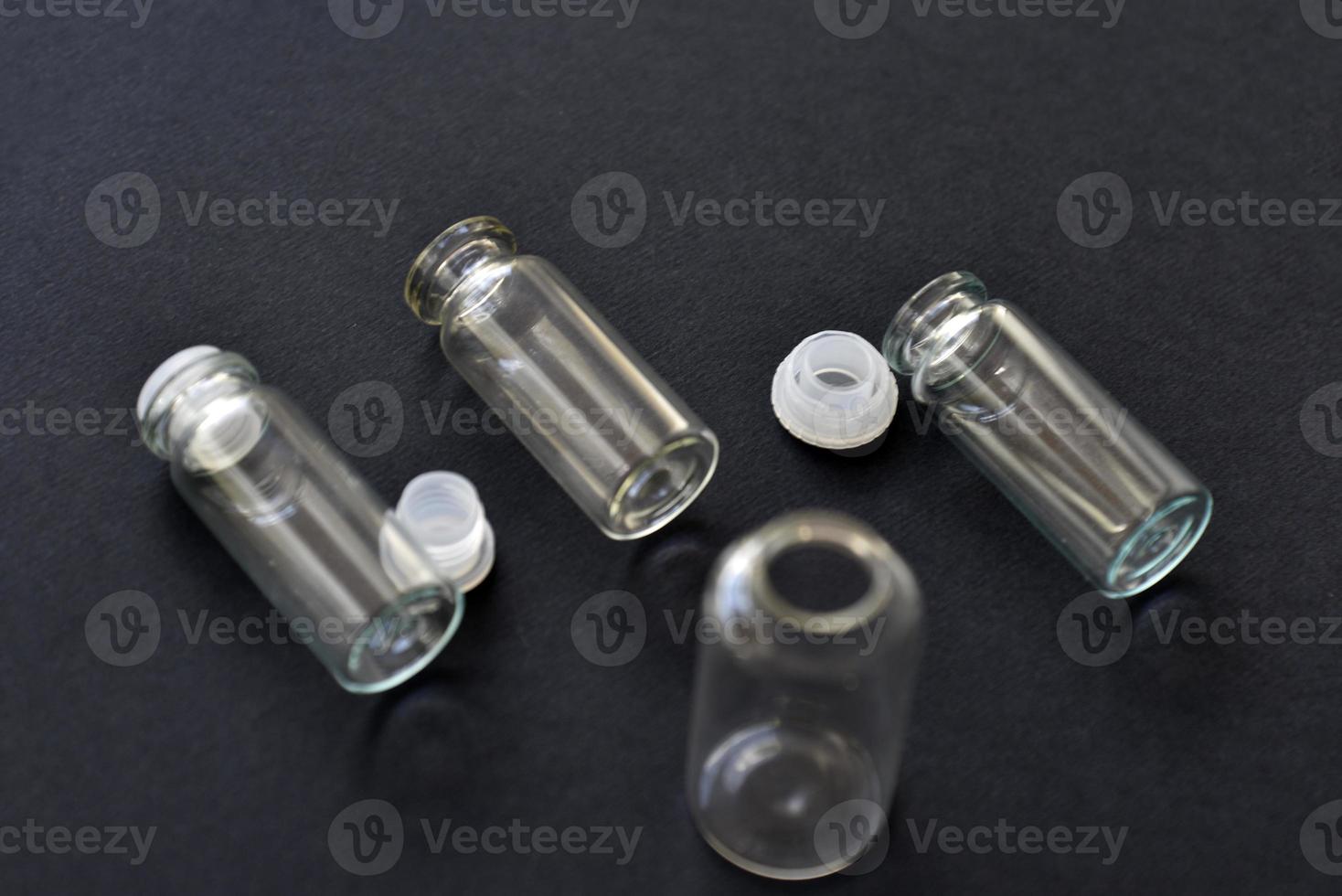 Glass empty bottles on a black background close-up. Pharmacy bottles in the afternoon in a group. photo