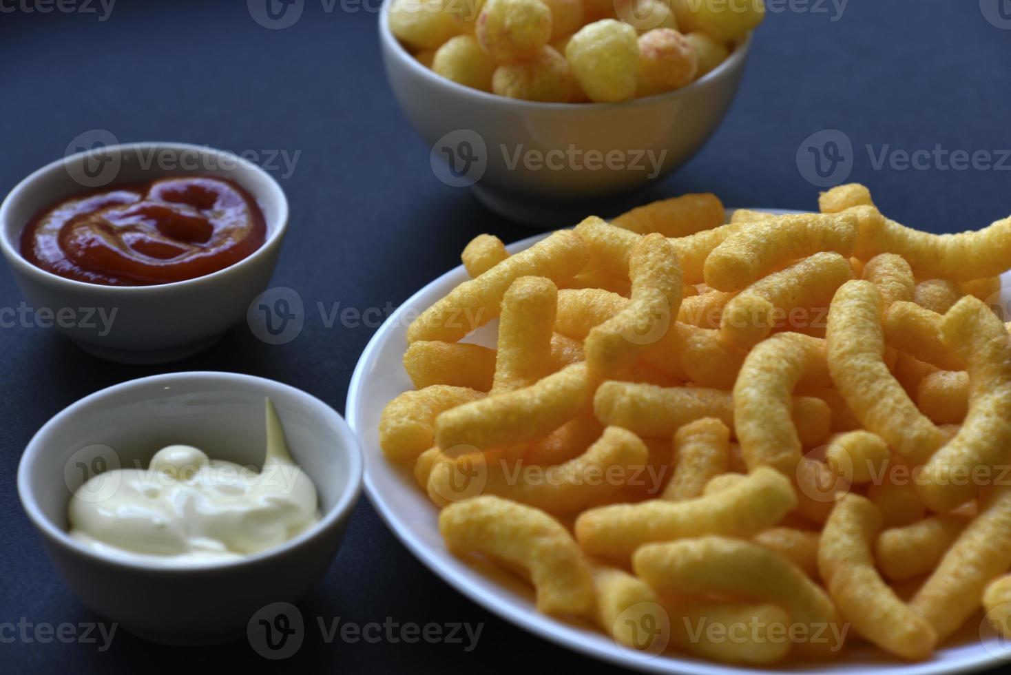 Peppered corn chips with sauce on a black background. Salty snack of corn snacks close-up. photo