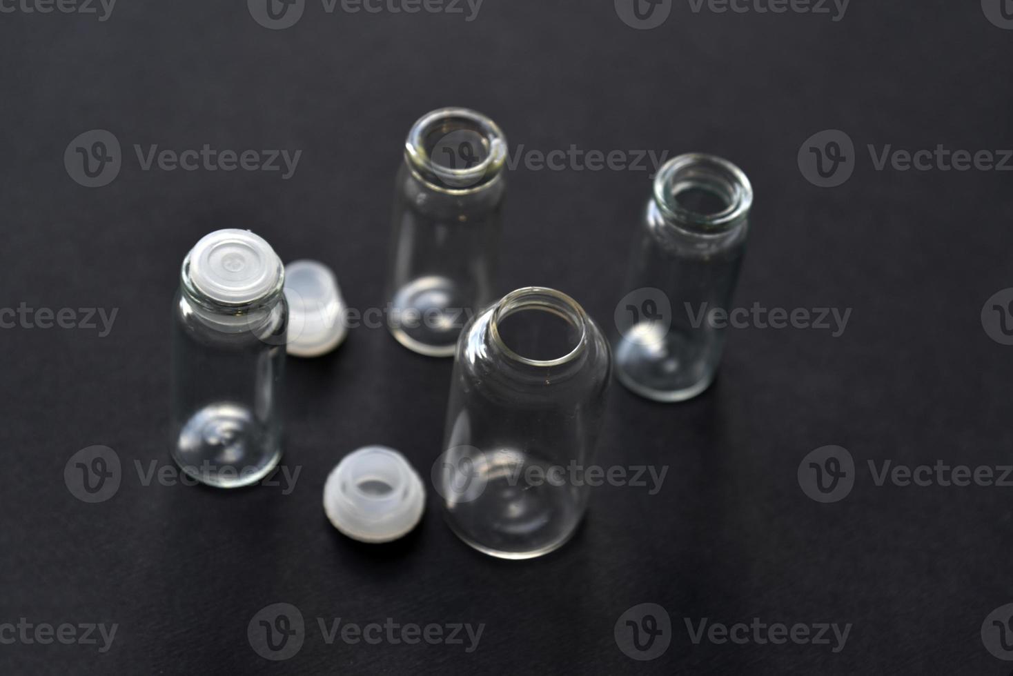 Glass empty bottles on a black background close-up. Pharmacy bottles in the afternoon in a group. photo