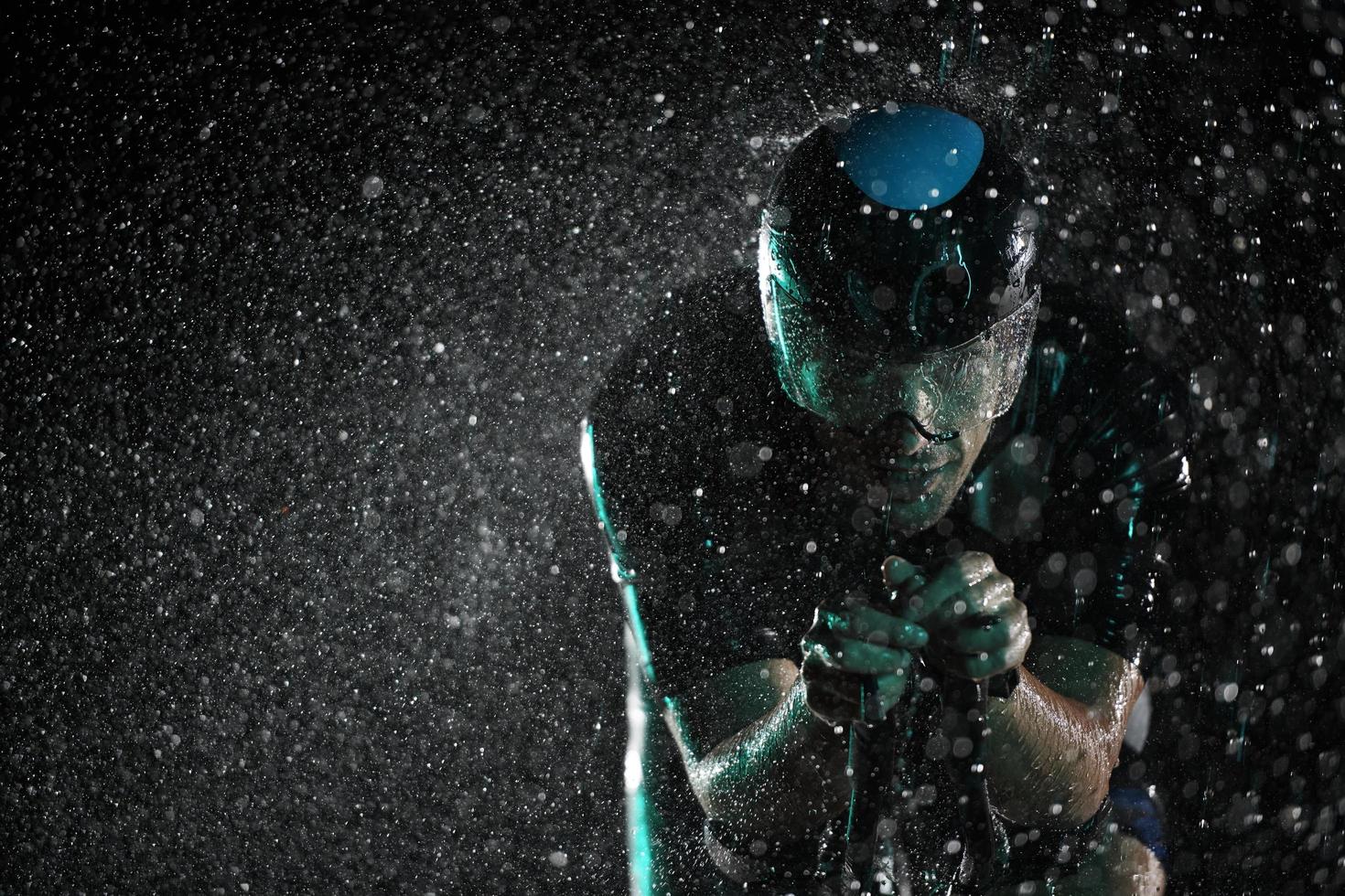 triathlon athlete riding bike  fast on rainy night photo