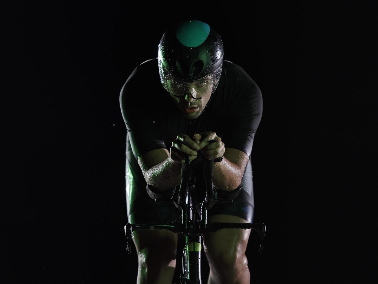 triathlon athlete riding bike fast at night photo