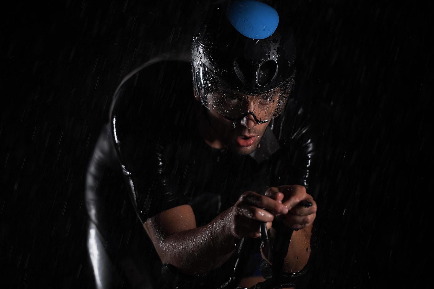 triathlon athlete riding bike  fast on rainy night photo