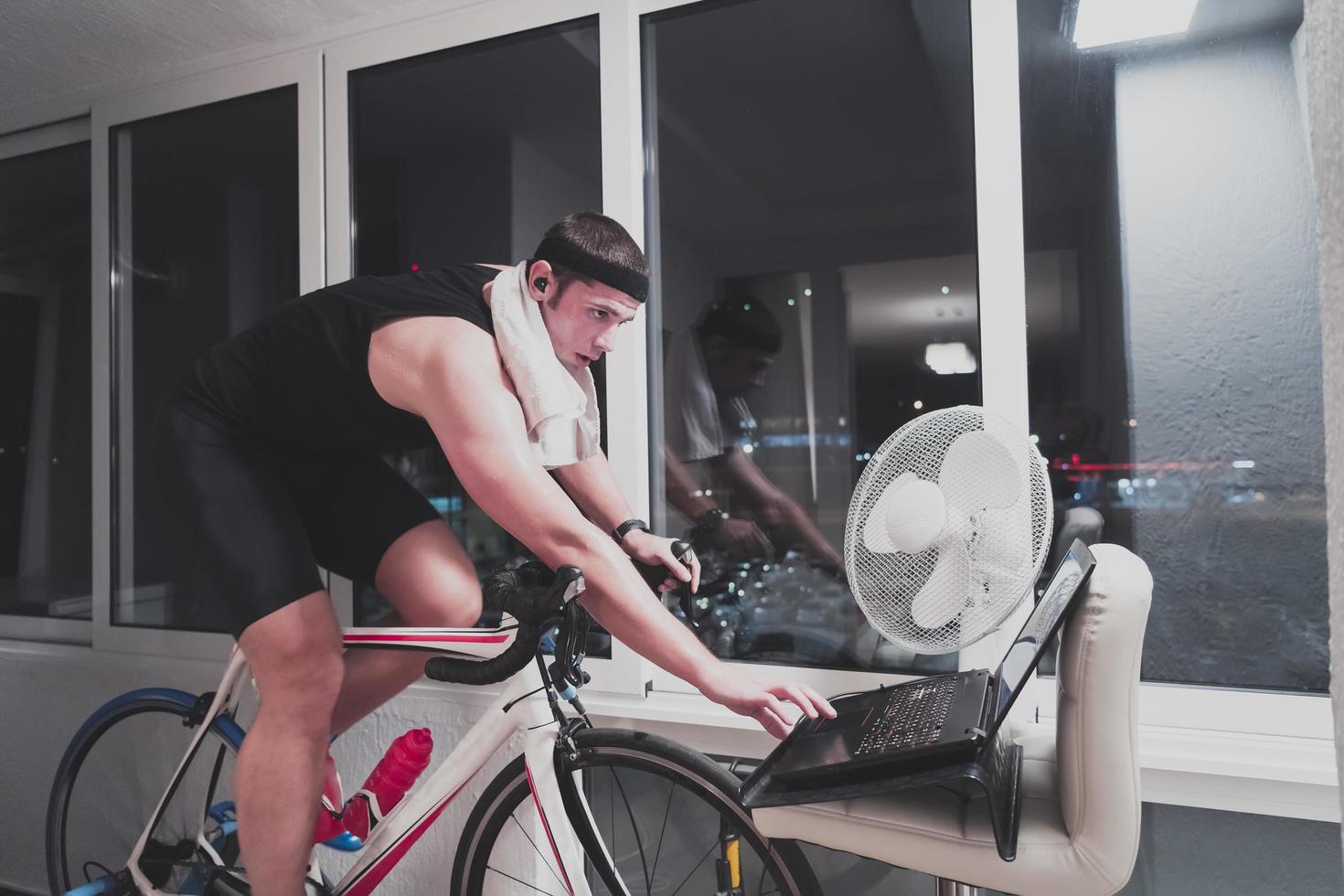 Man cycling on the machine trainer he is exercising in the home at night playing online bike racing game photo